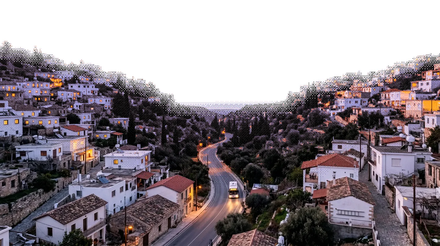 The same hill town at dusk, its windows and street lamps lit